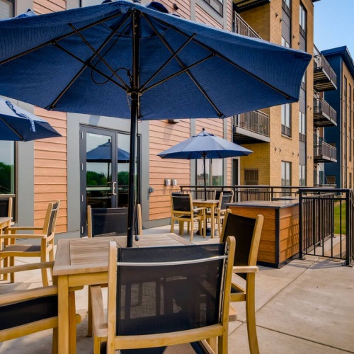 a patio with tables, chairs and umbrellas