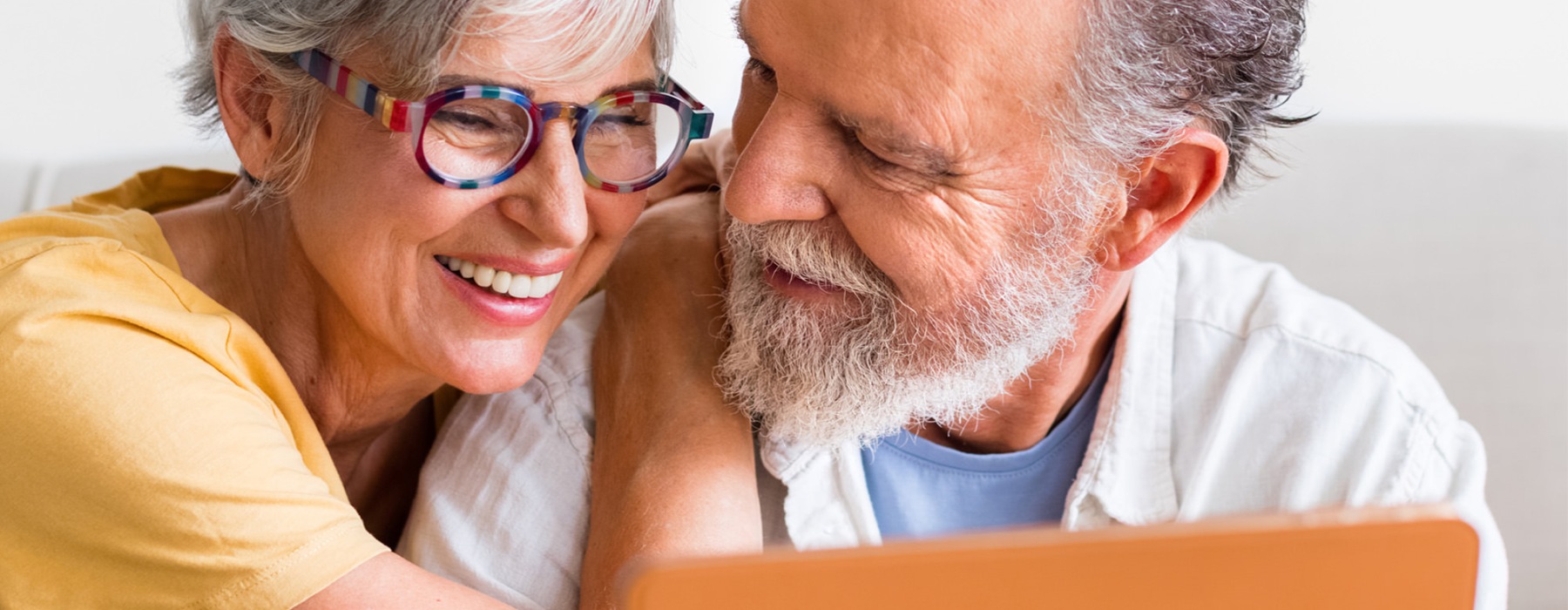 a man and a woman sitting on a couch looking at a tablet